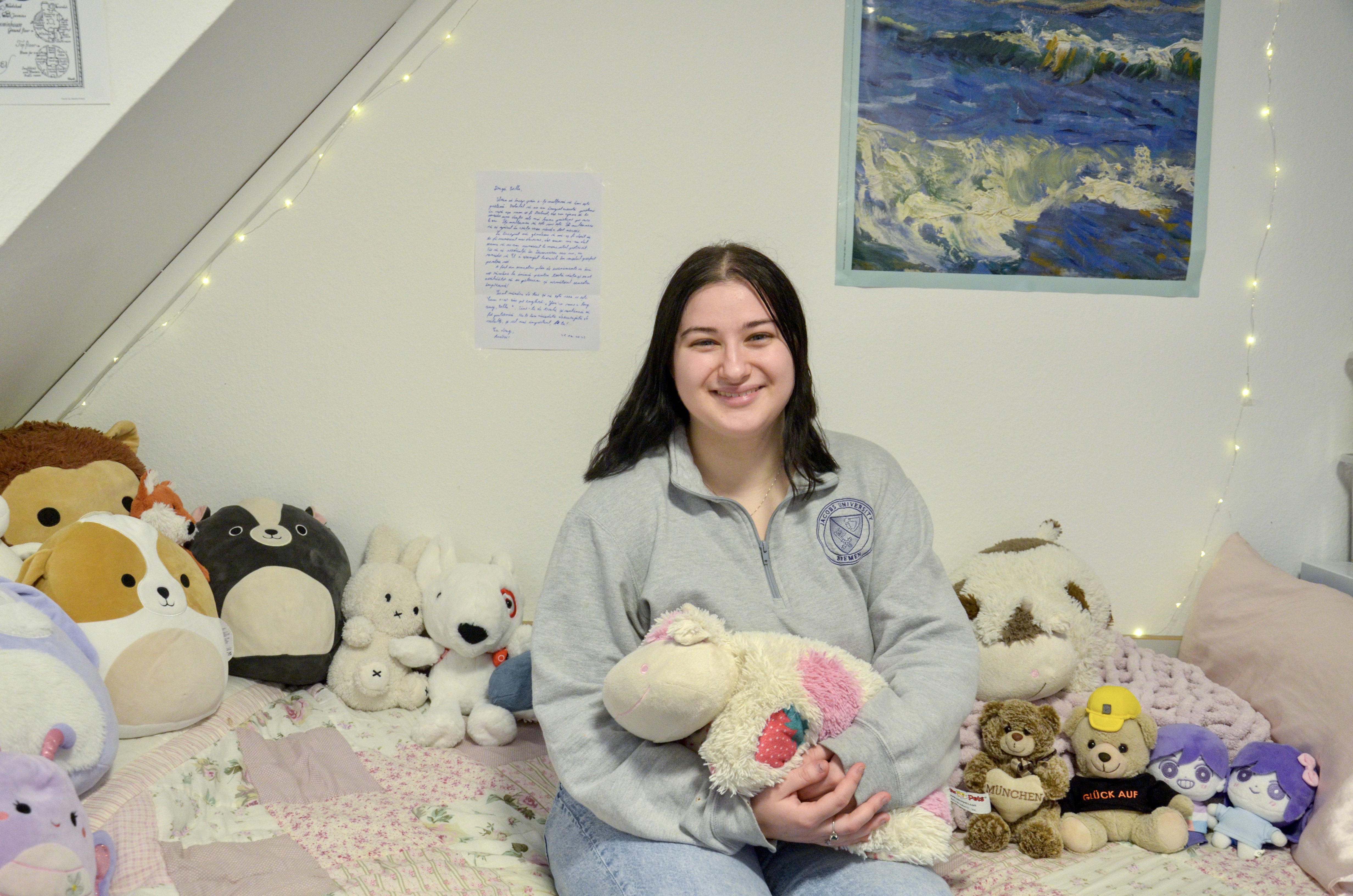 Student Bella sitting on her bed, surrounded by stuffed animals
